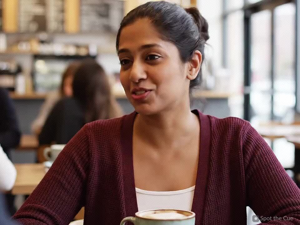 A person smiling warmly during a conversation at a café.