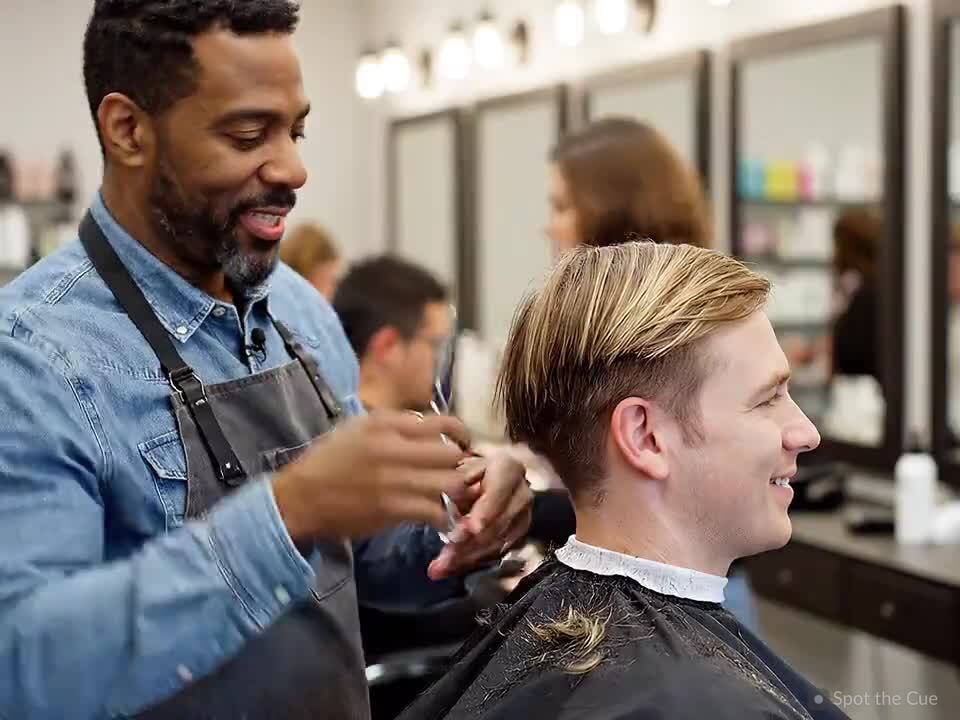 A stylist giving a client a haircut in a salon chair.